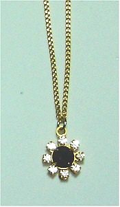 Small flower of rhinestone petals with black stone center on gold chain.